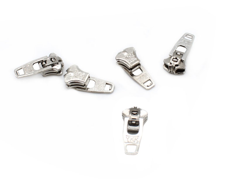 May include: Five silver zipper pulls with the brand name "YKK" printed on them.