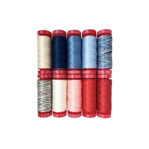 May include: Six spools of thread in various shades of blue, pink, and white. The spools are labeled "Aurifil" and "100% Cotton".