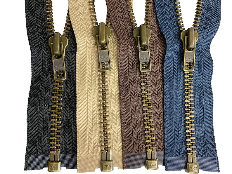 May include: Five zipper closures with brass sliders and teeth. The zippers are in black, beige, brown, and blue fabric.