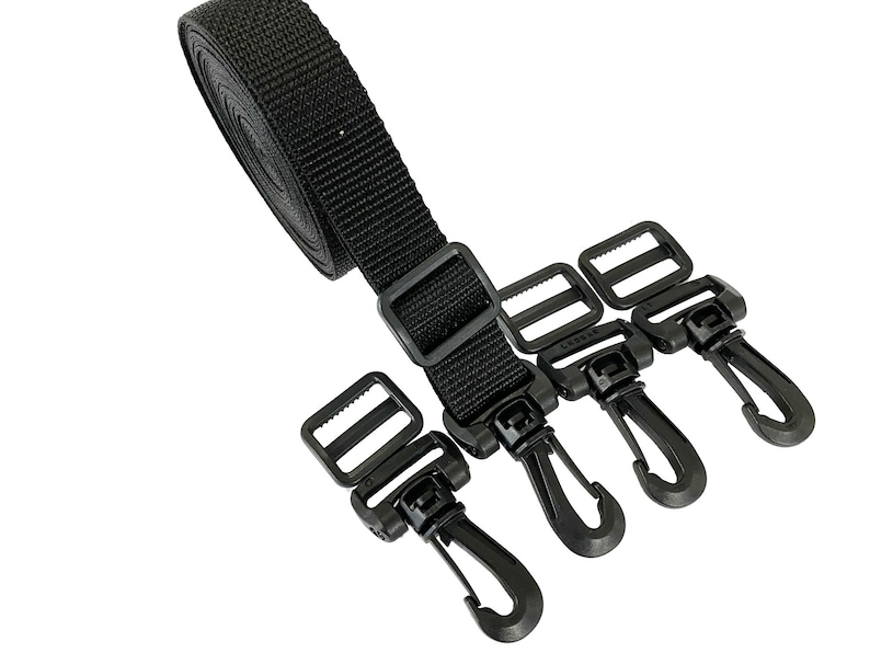 Puede incluir: Correa de nylon negra con tres clips de pl&aacute;stico negro. La correa est&aacute; enrollada y los clips est&aacute;n unidos a la correa.