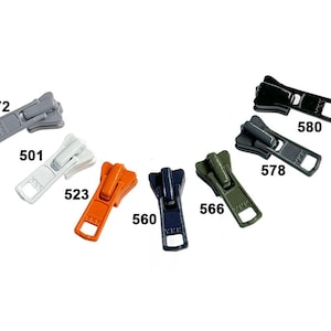 May include: Assortment of six zipper pulls in various colors, including gray, white, orange, dark blue, green, and black. Each pull has a number printed on it, such as 272, 501, 523, 560, 566, 578, and 580.