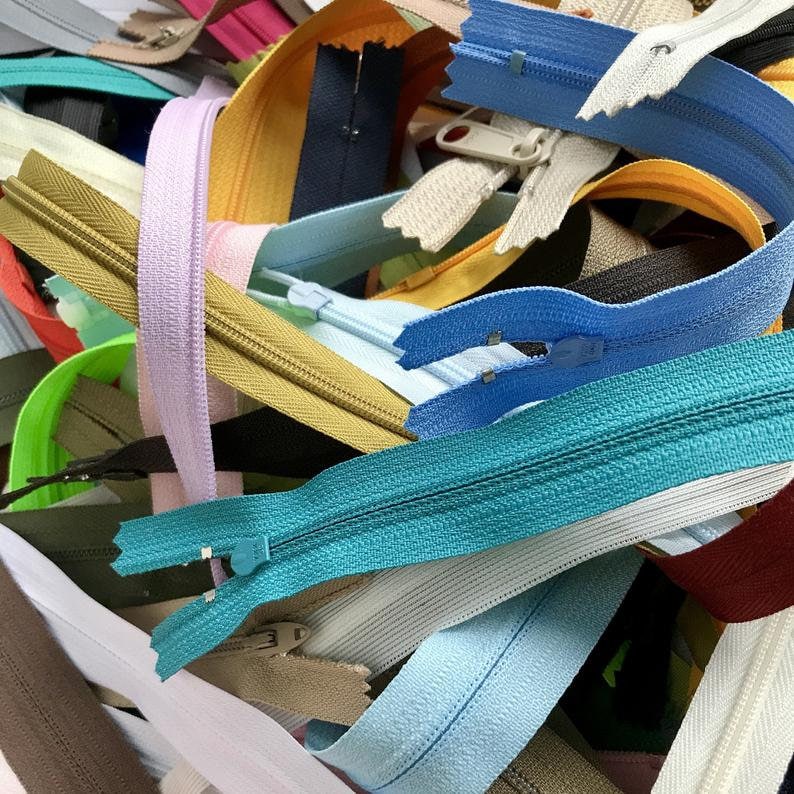 May include: A variety of zipper closures in different colors and lengths, including blue, green, yellow, and brown.