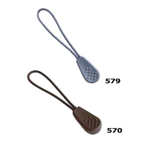 K&ouml;nnte beinhalten: Zwei Rei&szlig;verschluss-Zipper, einer grau und einer braun, mit einer strukturierten, runden Spitze. Der graue Rei&szlig;verschluss-Zipper hat die Nummer 579 darunter gedruckt, und der braune Rei&szlig;verschluss-Zipper hat die Nummer 570 darunter gedruckt.