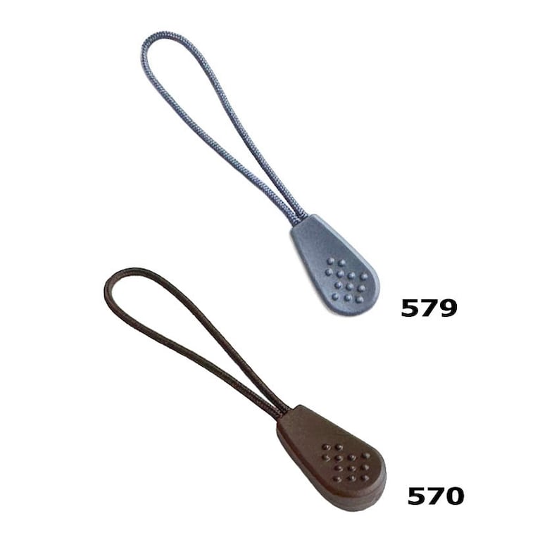 K&ouml;nnte beinhalten: Zwei Rei&szlig;verschluss-Zipper, einer grau und einer braun, mit einer strukturierten, runden Spitze. Der graue Rei&szlig;verschluss-Zipper hat die Nummer 579 darunter gedruckt, und der braune Rei&szlig;verschluss-Zipper hat die Nummer 570 darunter gedruckt.