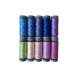 May include: A set of 10 spools of thread in various shades of blue, green, pink, and purple. The spools are labeled "Made in Italy" and "100% Cotton".