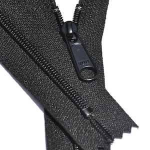 May include: A black zipper with a black metal slider. The zipper is open and the slider is in the middle of the zipper.