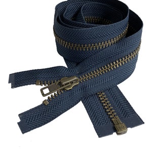 May include: A navy blue zipper with brass teeth and a slider. The zipper is coiled and ready to be sewn into a garment.