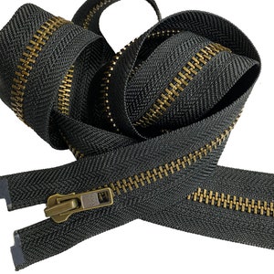 May include: A black zipper with a brass finish. The zipper is coiled and ready to be used for sewing projects.