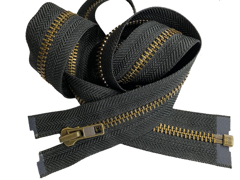 May include: A black zipper with a brass finish. The zipper is coiled and ready to be used for sewing projects.