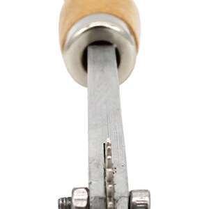 May include: A silver leather crafting tool with a wooden handle and a serrated blade. The tool is used for cutting leather.