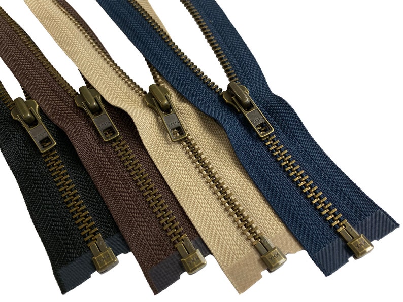 May include: Four zipper closures with antique brass sliders and teeth. The zippers are in different colors: black, brown, beige, and navy blue.