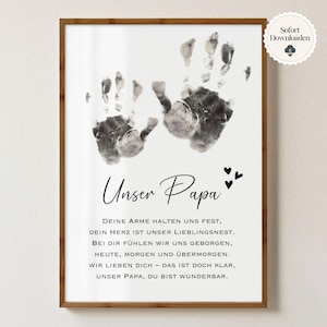 Può includere: Stampa incorniciata con cornice in legno marrone. La stampa presenta due impronte di mani in scala di grigi sopra le parole "Unser Papa" in elegante scrittura. Sotto, una poesia in tedesco e tre piccoli cuori.