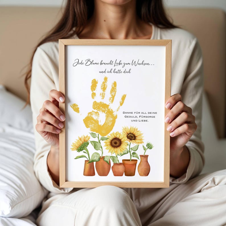 K&ouml;nnte beinhalten: Ein wei&szlig;er gerahmter Druck mit einem gelben Handabdruck und Sonnenblumen. Der Text lautet "Jede Blume braucht liebe zum Wachsen... und ich hatte dich DANKE F&Uuml;R ALL DEINE GEDULD, F&Uuml;RSORGE UND LIEBE."