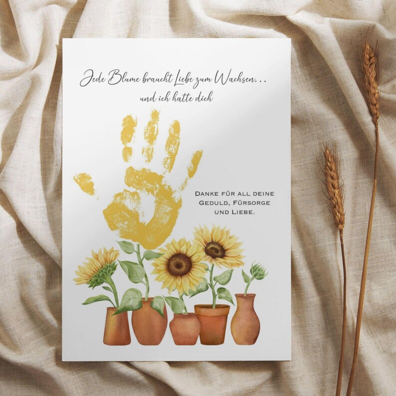 K&ouml;nnte beinhalten: Eine wei&szlig;e Karte mit einem gelben Handabdruck und einer Nachricht, die lautet "Jede Blume braucht Liebe zum Wachsen... und ich hatte dich. DANKE F&Uuml;R ALL DEINE GEDULD, F&Uuml;RSORGE UND LIEBE." Der Handabdruck ist von f&uuml;nf gelben Sonnenblumen in T&ouml;pfen umgeben.