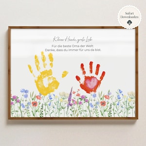 May include: A framed print with a wooden border. The print features two handprints, one yellow and one red, above a floral border. Text in German reads, "Small hands, great love" and a message for the best grandma.