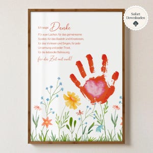 Könnte beinhalten: Ein gerahmter Druck mit einem Aquarelldesign. Der Druck zeigt einen roten Handabdruck mit einem Herz in der Mitte, umgeben von bunten Blumen. Der deutsche Text enthält das Wort "Danke" und eine Botschaft der Dankbarkeit.