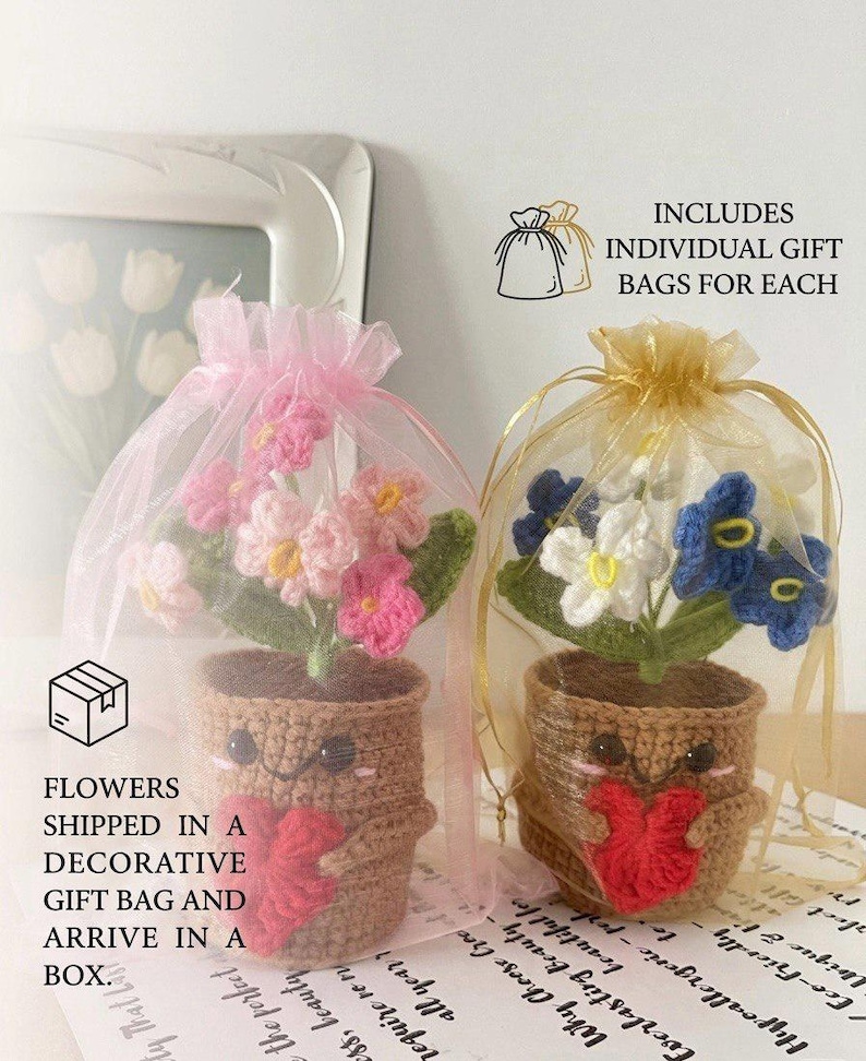 May include: Two crocheted potted plants with smiling faces, each holding a red heart. One plant has pink flowers in a pink organza bag, and the other has blue and white flowers in a gold organza bag. Text includes INCLUDES INDIVIDUAL GIFT BAGS FOR EACH.