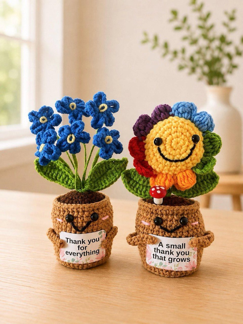 May include: Two crocheted potted plants with smiling faces. The left plant has blue flowers and a sign reading "Thank you for everything." The right plant has a multi-colored flower, a small mushroom, and a sign reading "A small thank you that grows."