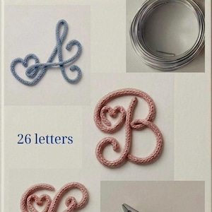 Op de afbeelding: Een boekomslag met de titel TRICOTIN CREATIONS: Mastering the Art of Knitted Cord Letters, A COLLECTION OF PATTERNS AND IDEAS, 26 letters. Het toont een blauwe letter A, een roze letter B, een roze letter C, zilverkleurig draad en een tang.