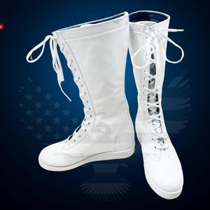 May include: A pair of white wrestling boots with laces up the front. The boots have a flat sole and are made of a smooth leather-like material.