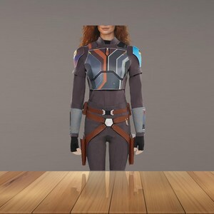 Puede incluir: Un disfraz gris oscuro y marr&oacute;n con una placa pectoral, una armadura para los hombros y un cintur&oacute;n. El disfraz tiene un dise&ntilde;o futurista con detalles plateados, naranjas y azules. El modelo lleva guantes negros.