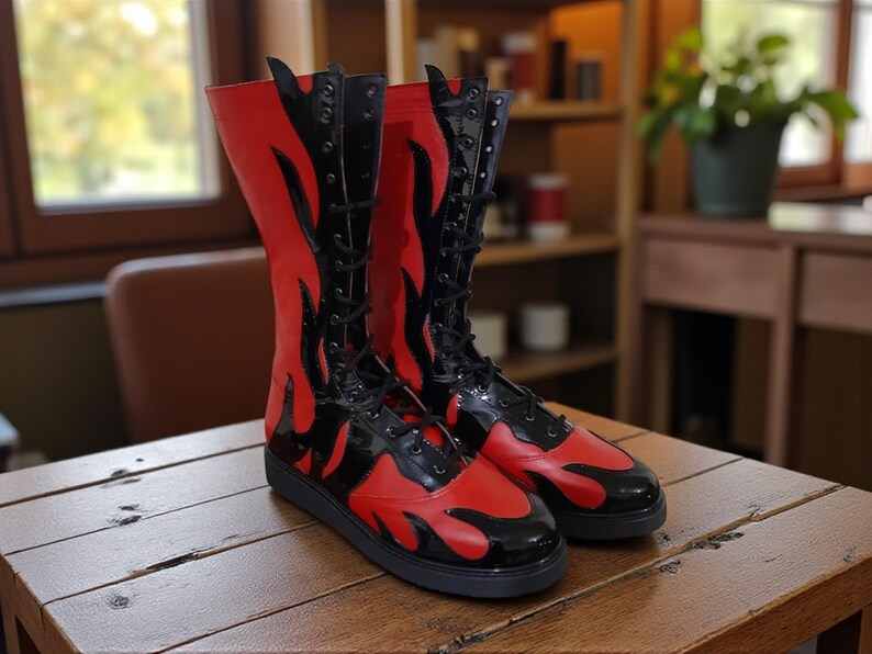 May include: A pair of tall, red and black boots with a flame design. The boots have a lace-up closure and a black sole. The boots are made of a shiny material and are displayed on a wooden surface.