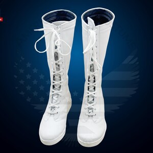 May include: A pair of white leather knee-high boots with lace-up fronts. The boots have a blue lining and are on a blue background.