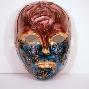 May include: A Venetian masquerade mask with intricate gold and blue designs on a red and blue background.