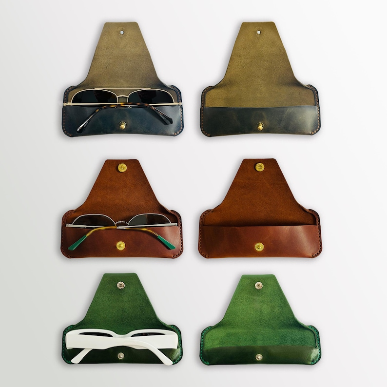 K&ouml;nnte beinhalten: Sechs Lederbrillenetuis in verschiedenen Farben. Die Etuis sind ge&ouml;ffnet und zeigen das Innenfutter. Die Etuis haben alle die gleiche Form und Gr&ouml;&szlig;e. Die Etuis sind aus braunem, gr&uuml;nem und blauem Leder.