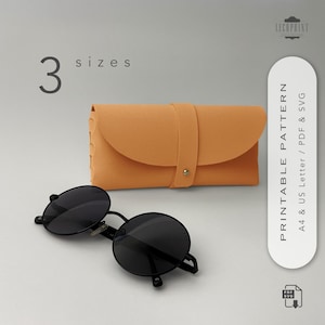 Può includere: Occhiali da sole rotondi neri e una custodia arancione con cinturino e bottone dorato. L'immagine include anche il testo "3 taglie" e "PRINTABLE PATTERN A4 & US Letter / PDF & SVG". La custodia è progettata per contenere gli occhiali da sole.