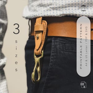 May include: A close-up of a tan leather belt with a matching leather key holder and a gold-colored clasp. The key holder is attached to the belt. The text "3 sizes" is on the left side. The text "PRINTABLE PATTERN" is on the right side.