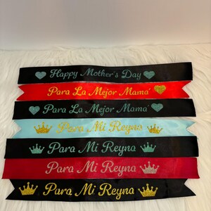 May include: A set of eight black and red satin ribbon sashes with gold glitter lettering. The sashes have different messages, including "Happy Mother's Day", "Para La Mejor Mama", and "Para Mi Reyna".
