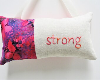 hand-embroidered hanging pillow- "strong'' on natural linen and bright fuschia, orange, purple batik print, inspirational, meditation