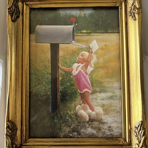 May include: A framed painting depicts a young child in a pink dress with white trim, reaching for a letter at a mailbox. The mailbox is silver, set against a rural backdrop of green and yellow fields. The frame is ornate, gold-colored, and adds a decorative touch.