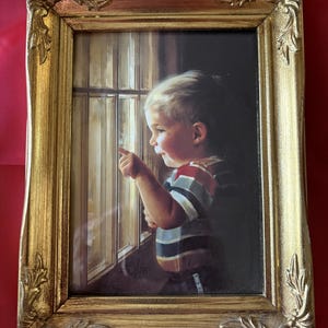 May include: A framed painting of a young child looking out a window, pointing with their index finger. The child wears a striped shirt. The ornate gold frame adds a classic touch to the artwork.