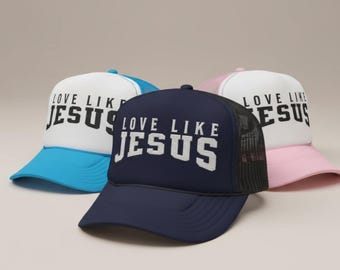 May include: Three trucker hats with the text "LOVE LIKE JESUS" in white block letters. The hats are navy blue, light blue, and pink, with white front panels and black mesh backs. The hats are a religious theme.