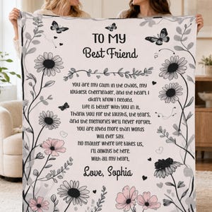 Peut inclure: Une couverture blanche en polaire ornée de dessins au trait noir représentant des marguerites et des papillons sur les bords. Le centre affiche le texte TO MY BEST FRIEND suivi d'un message sentimental et la signature Love, Sophia.