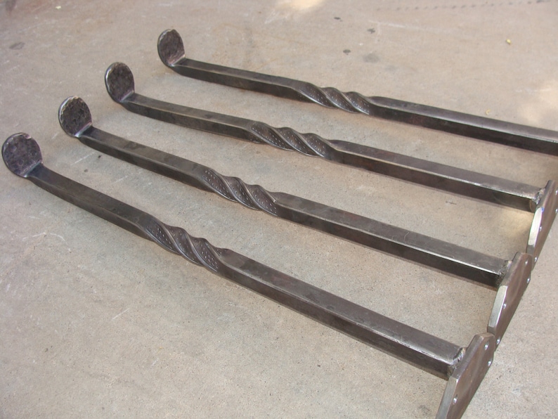 May include: Four metal table legs with a twisted design. The legs are made of dark metal and have a hammered finish.
