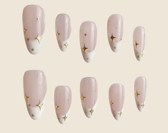 May include: Set of ten false nails with a light pink base and white tips. Each nail has a gold star design.