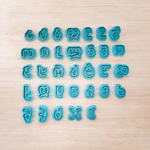 May include: A set of 30 blue plastic cookie cutters shaped like letters of the Georgian alphabet.