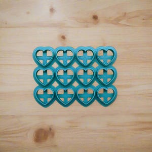 Op de afbeelding: Teal gekleurde plastic mal met 16 hartvormige holtes. De mal is ontworpen voor het maken van koekjes, fondant of andere eetbare lekkernijen.
