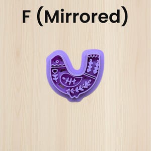 Puede incluir: Un cortador de galletas morado con forma de p&aacute;jaro con dise&ntilde;os florales y geom&eacute;tricos. El texto "F (Mirrored)" est&aacute; en la parte superior de la imagen. El cortador est&aacute; sobre una superficie de madera clara.