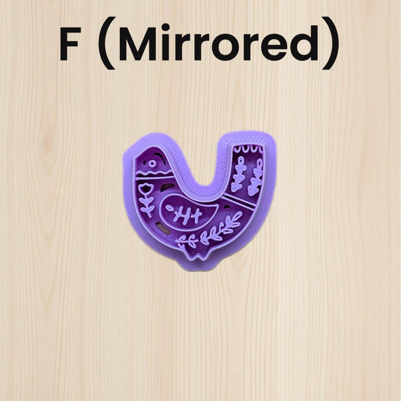 Puede incluir: Un cortador de galletas morado con forma de p&aacute;jaro con dise&ntilde;os florales y geom&eacute;tricos. El texto "F (Mirrored)" est&aacute; en la parte superior de la imagen. El cortador est&aacute; sobre una superficie de madera clara.