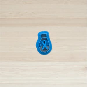 May include: A blue cookie cutter in the shape of a lightbulb with a blue ribbon inside. The cookie cutter is made of plastic and is designed to cut out cookies in the shape of a lightbulb with a ribbon.