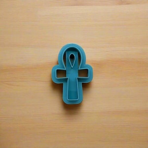 May include: A blue plastic cookie cutter shaped like an Ankh, an ancient Egyptian symbol of life.