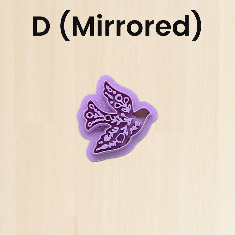 Puede incluir: Un cortador de galletas morado con forma de p&aacute;jaro con intrincados patrones florales y de hojas. El cortador tiene un dise&ntilde;o de espejo y est&aacute; sobre un fondo de madera clara. El texto "D (Mirrored)" est&aacute; en la parte superior.