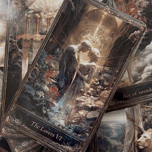 May include: A collection of tarot cards featuring intricate dark gold and black ornate borders. The central card displays The Lovers VI with two figures embracing amidst flowers. Other visible cards include Ace of Swords and Strength VIII.