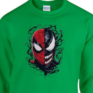 May include: Green sweatshirt featuring a split face design of Spider-Man and Venom. The Spider-Man side is red and black, while the Venom side is black and white with sharp teeth. The graphic is centered on the chest.