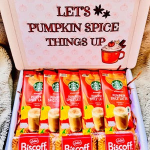 May include: A gift box containing five Starbucks Pumpkin Spice Latte instant coffee packets and three Lotus Biscoff cookie packs. The box lid features the text "LET'S PUMPKIN SPICE THINGS UP" with a graphic of a mug and pumpkin pattern.