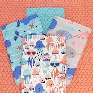 May include: A set of five fabric squares featuring a variety of colorful sea creatures and patterns. The fabrics include a blue and white pattern with jellyfish, a blue and white pattern with whales, a gray and white pattern with narwhals, a blue and white pattern with waves, and a blue and white pattern with fish.